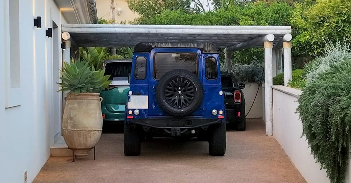 Timber pergola carport shading three vehicles at a villa.
